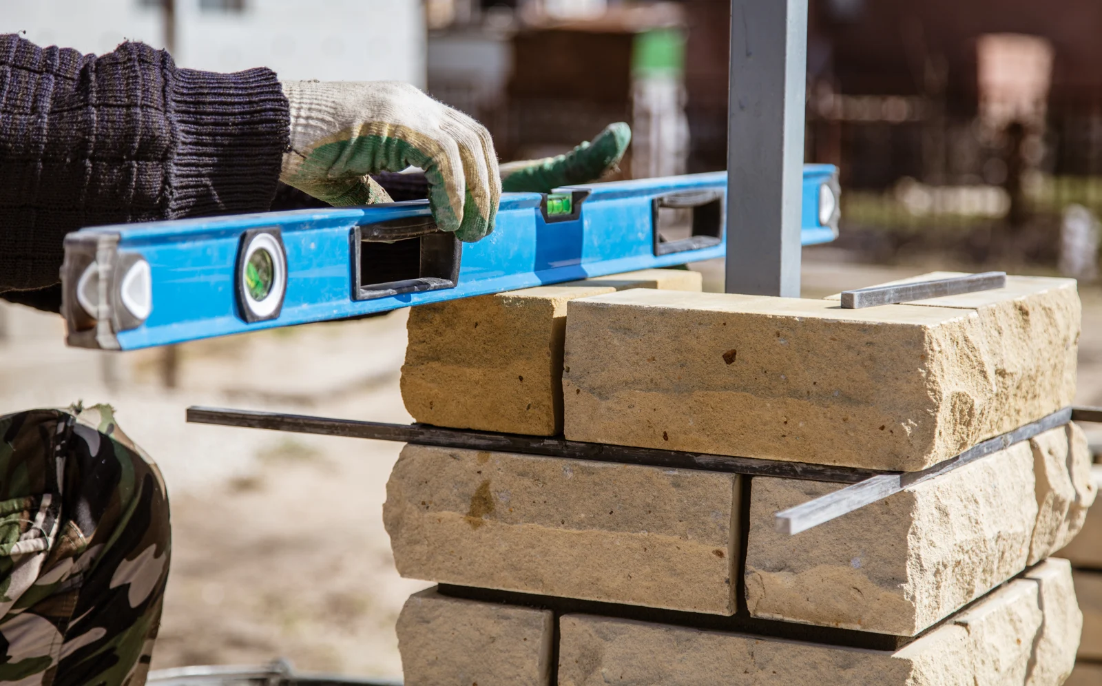 A gloved hand checking stonework with a spirit level.